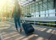 Woman pulling luggage and carry-on essentials through an airport.