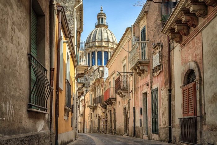 Photo of a narrow street scene, in Ragusa, Sicily.